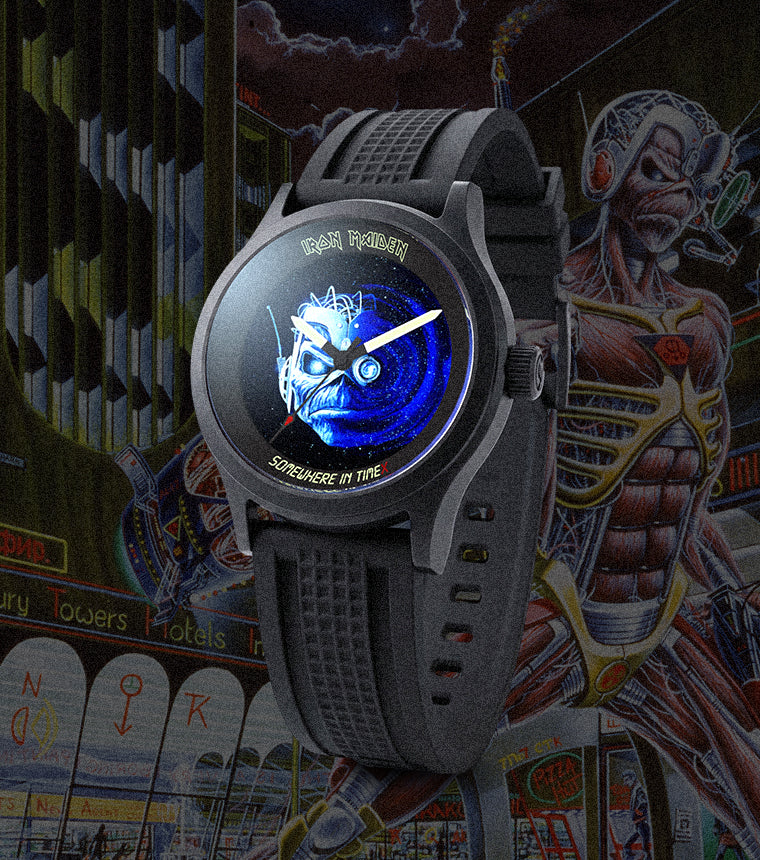 Close-up of the Timex x Iron Maiden 1986 Tribute watch with a glowing blue Eddie dial, set against a dark cyberpunk-style city scene featuring Iron Maiden’s Eddie character in the background.