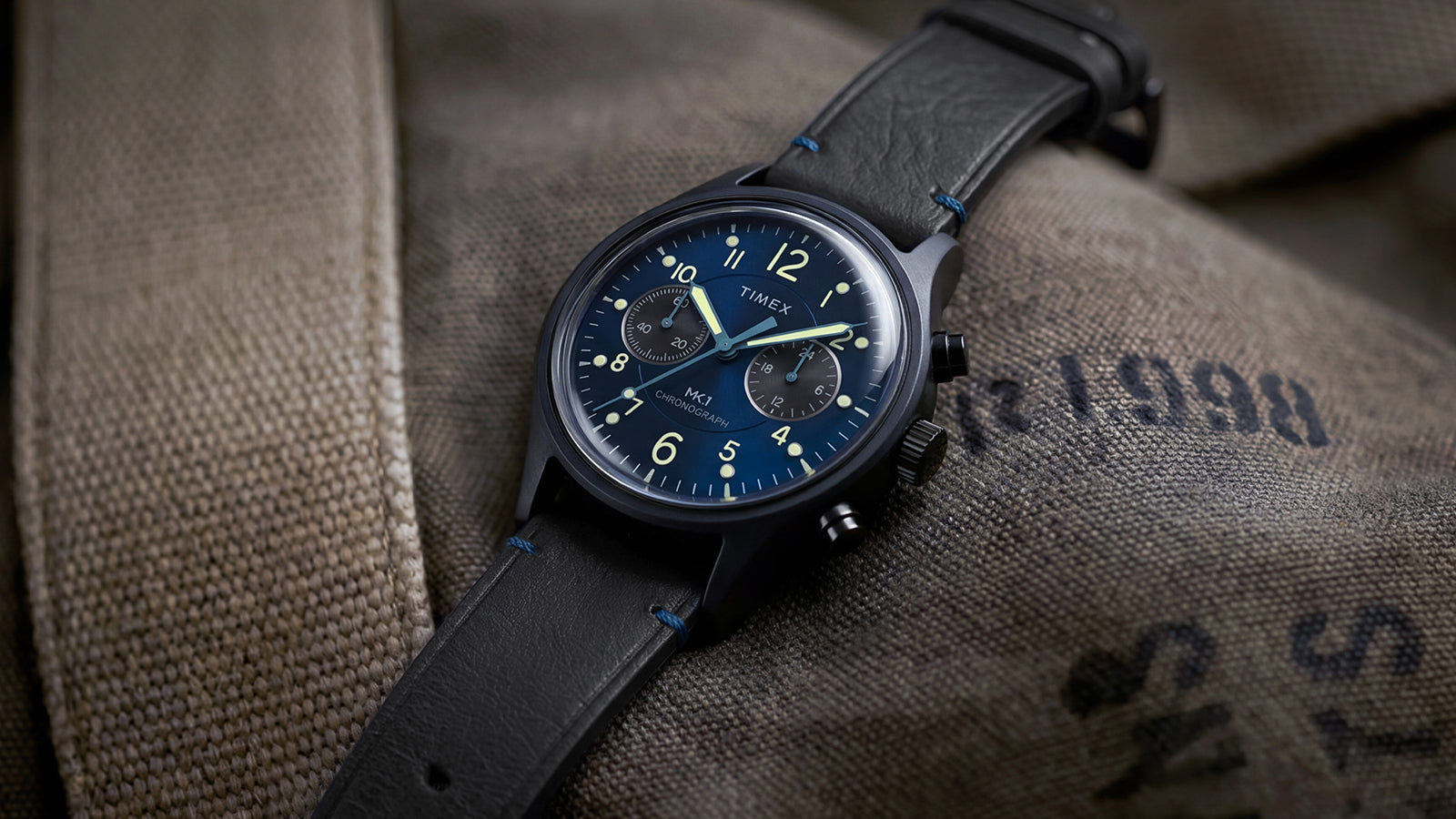 Close-up of the Timex MK1® Chronograph featuring a blue dial, chronograph subdials, black case, and black leather strap.