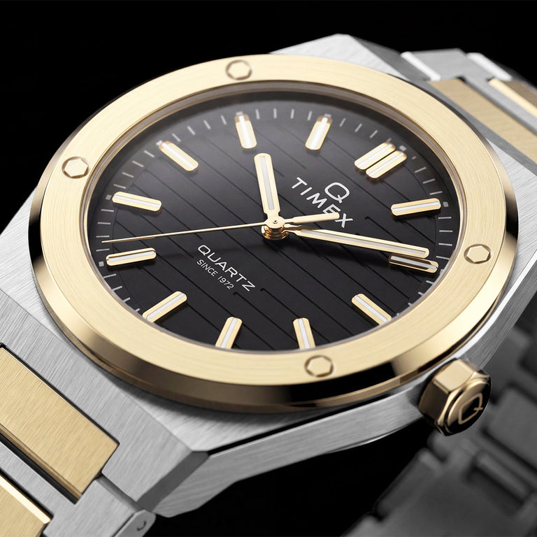 Close-up of the Timex Q Marbella black textured dial with a brushed gold-tone bezel and two-tone stainless steel bracelet.