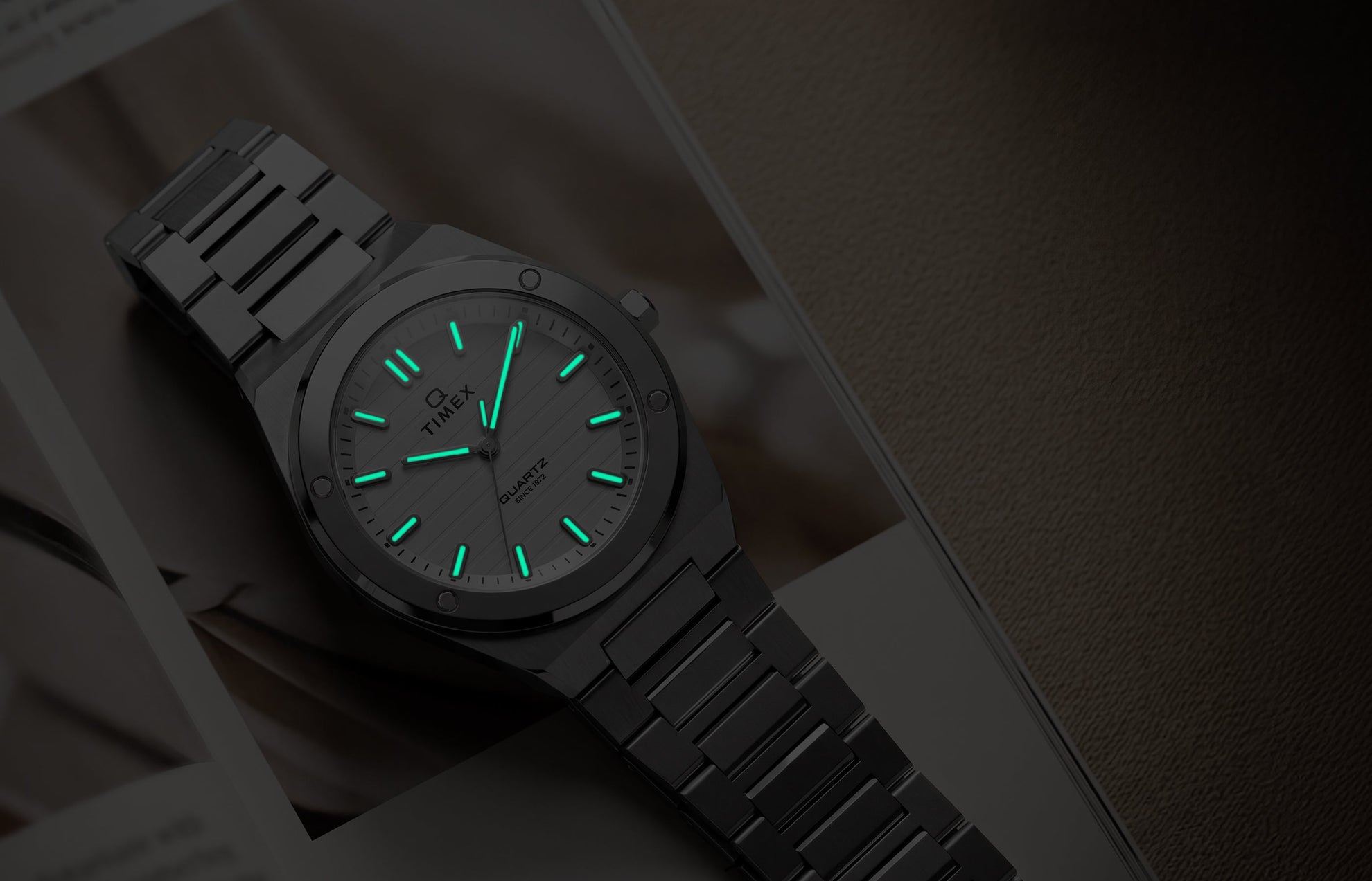 Q Timex Marbella stainless steel watch with glowing Indiglo® hands and hour markers in low light.