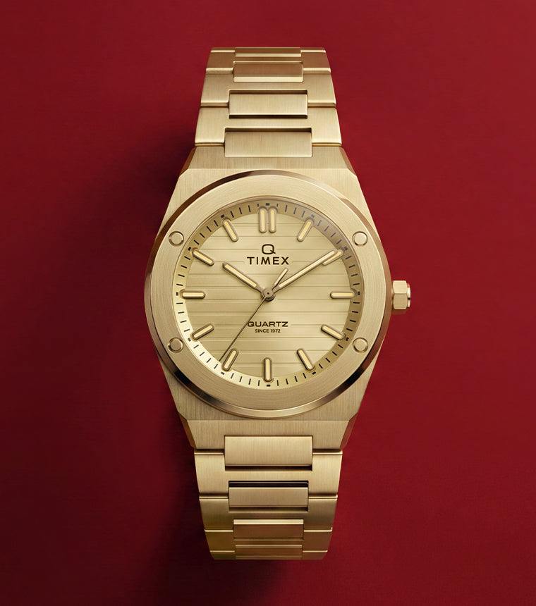 Front view of the Q Timex Marbella gold-tone stainless steel watch featuring a champagne dial and integrated bracelet.