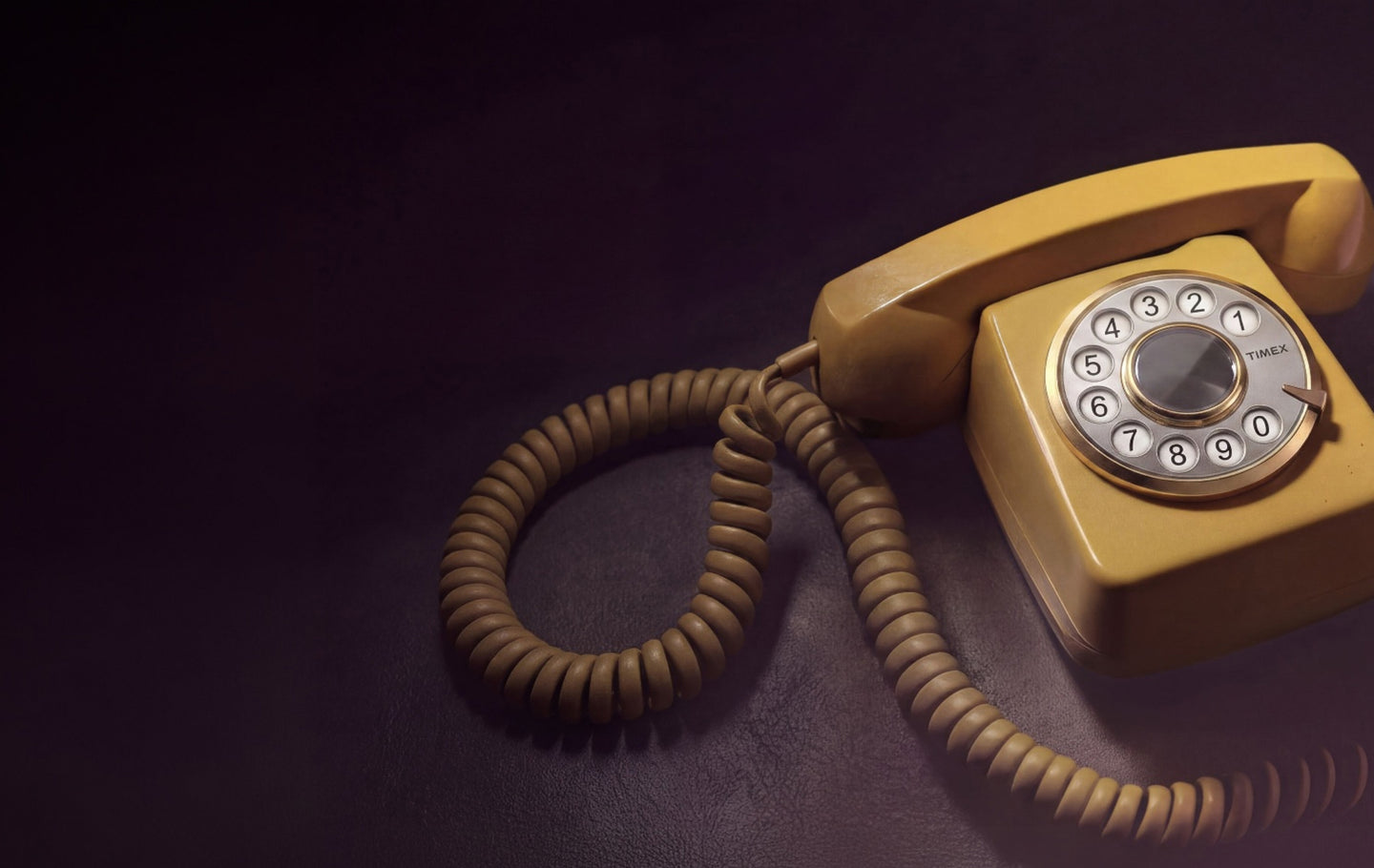 Vintage rotary telephone with a Timex-branded rotary dial displayed on a dark surface, featuring a coiled cord and warm retro lighting.