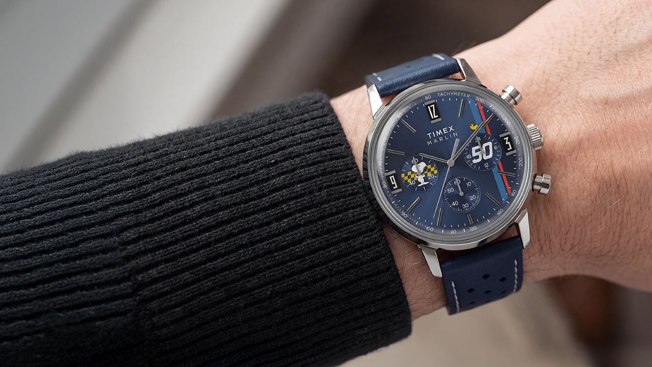 Peanuts® x Timex Marlin® Chronograph on the wrist featuring a blue dial, silver-tone stainless steel case, and perforated blue leather strap.