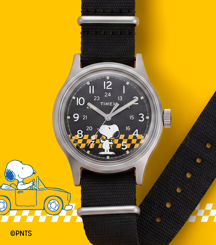 Peanuts® x Timex MK1® watch with a black fabric strap, black dial featuring Snoopy in sunglasses, and a yellow racing-inspired background with checkered graphics.