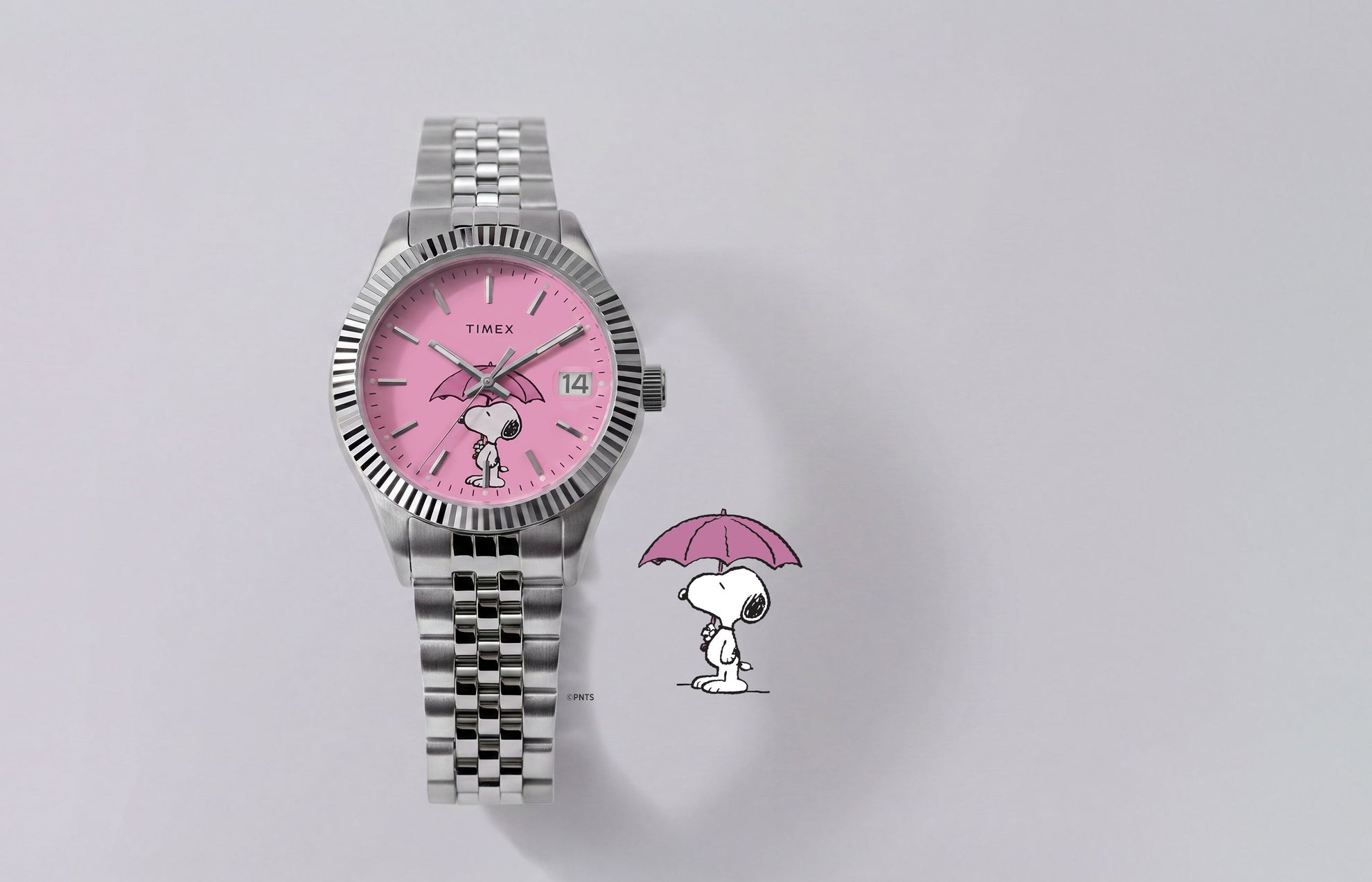 Peanuts® x Timex Legacy Snoopy Umbrella watch with a pink dial, stainless steel bracelet, and Snoopy holding a pink umbrella beside the watch.