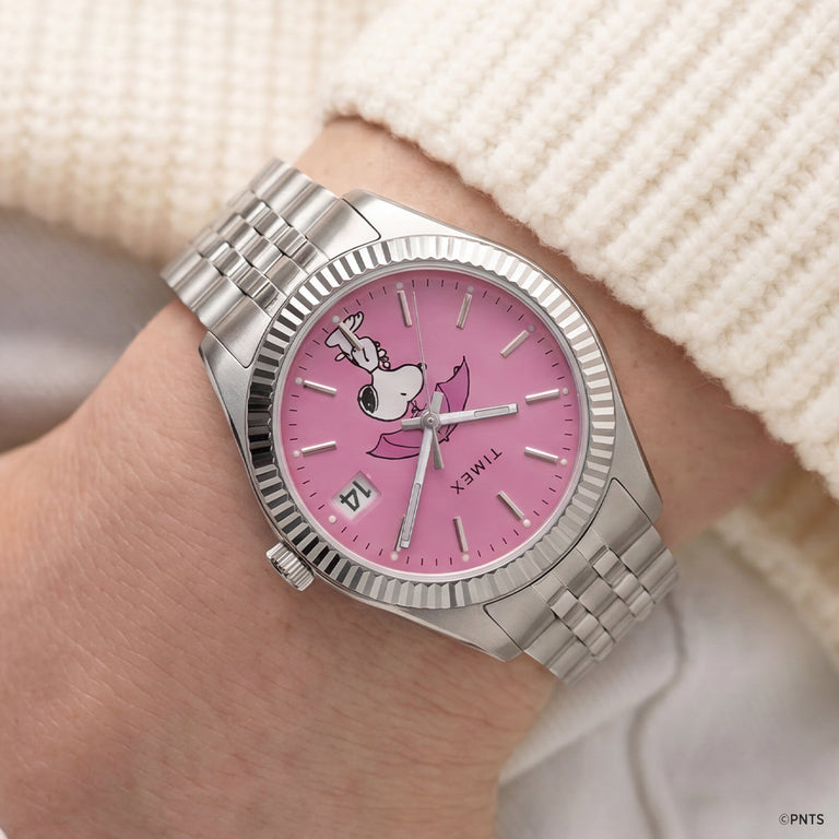 Peanuts® x Timex Legacy Snoopy Umbrella watch worn on the wrist, showcasing the pink dial with Snoopy holding a pink umbrella and a stainless steel bracelet.