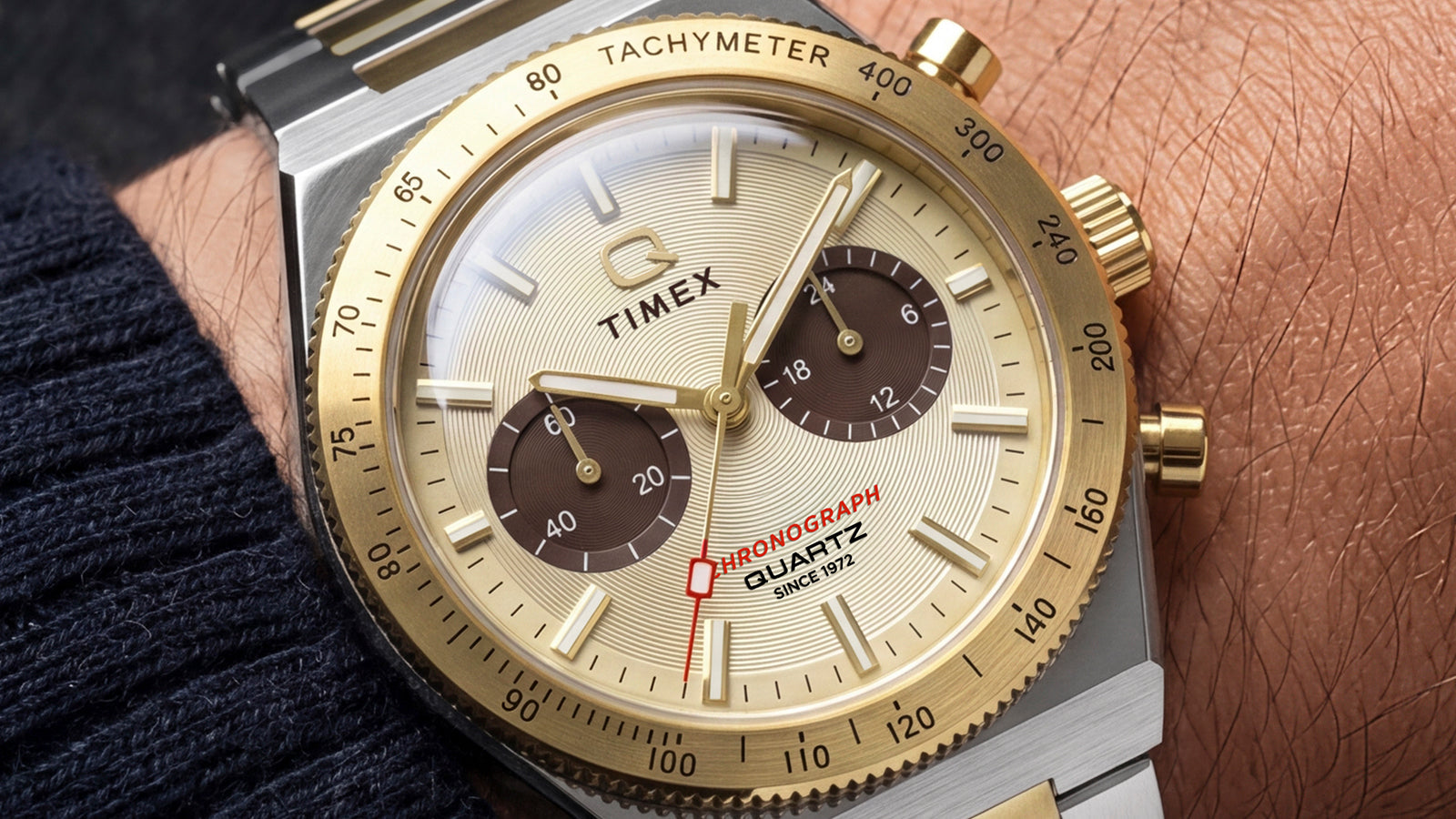 Close-up of the Q Timex Continental Chronograph on a wrist, highlighting its champagne dial, brown subdials, and gold-tone tachymeter bezel.