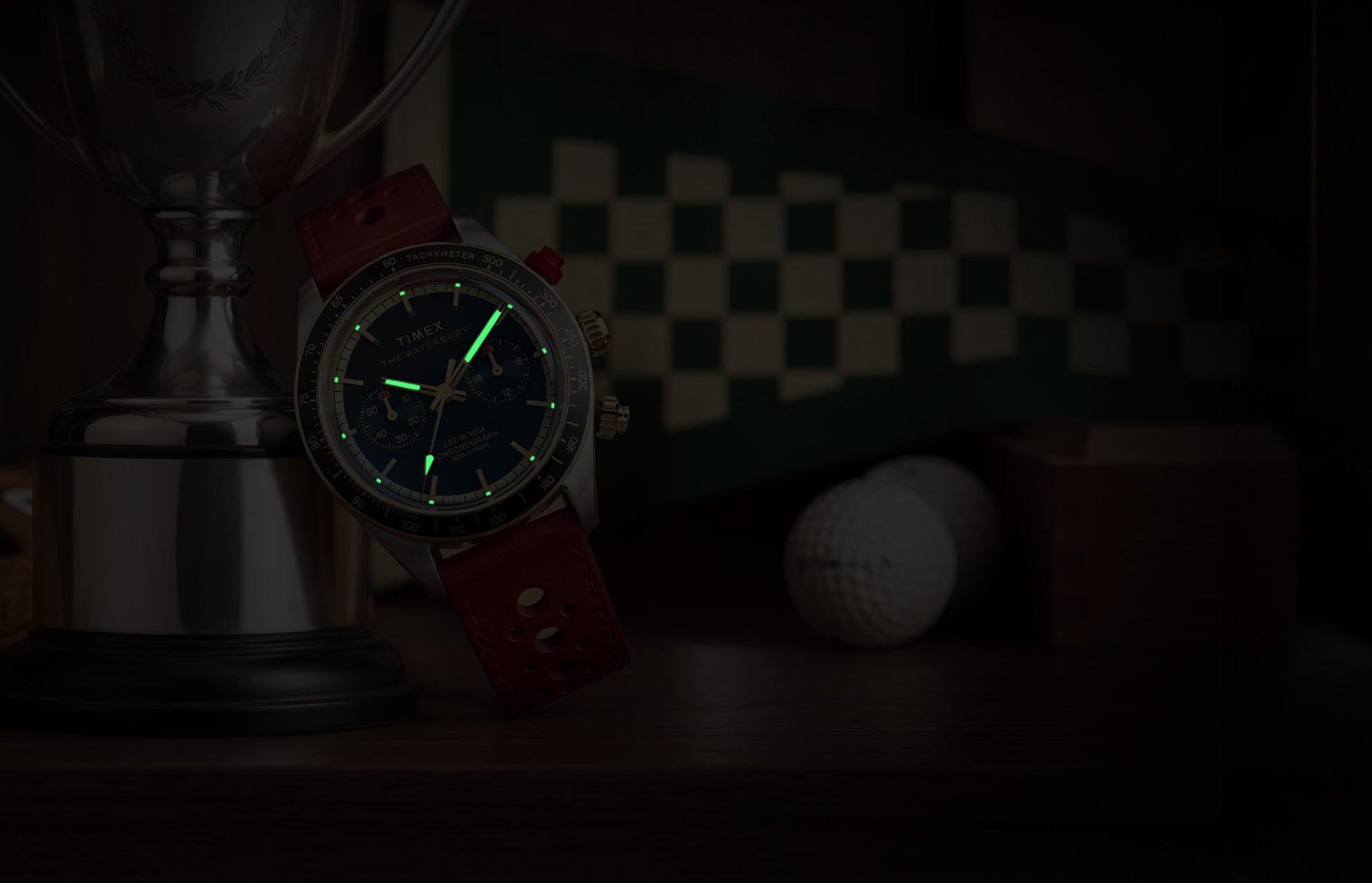 Waterbury Heritage Chronograph in a dark setting, highlighting the green luminous hands and hour markers on the blue dial.