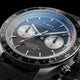 Close-up of the Timex Waterbury Heritage Chronograph featuring a black and silver panda-style dial, dual chronograph sub-dials, tachymeter bezel, and red chronograph accents.