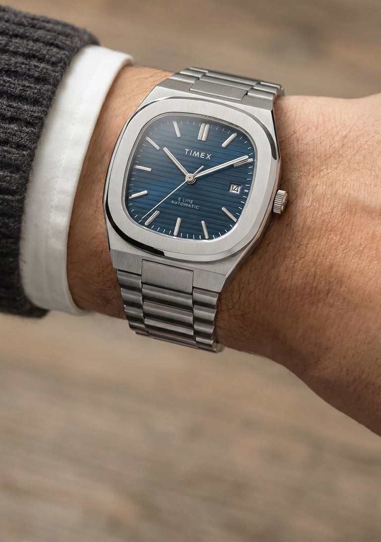 Timex Automatic E Line 38mm with a blue dial and stainless-steel bracelet, shown on the wrist.