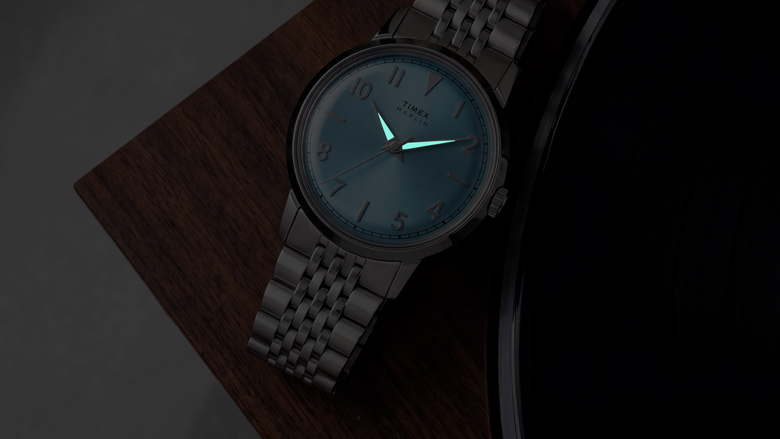 Timex Marlin Quartz with luminous hands illuminated in low light against an ice blue dial.