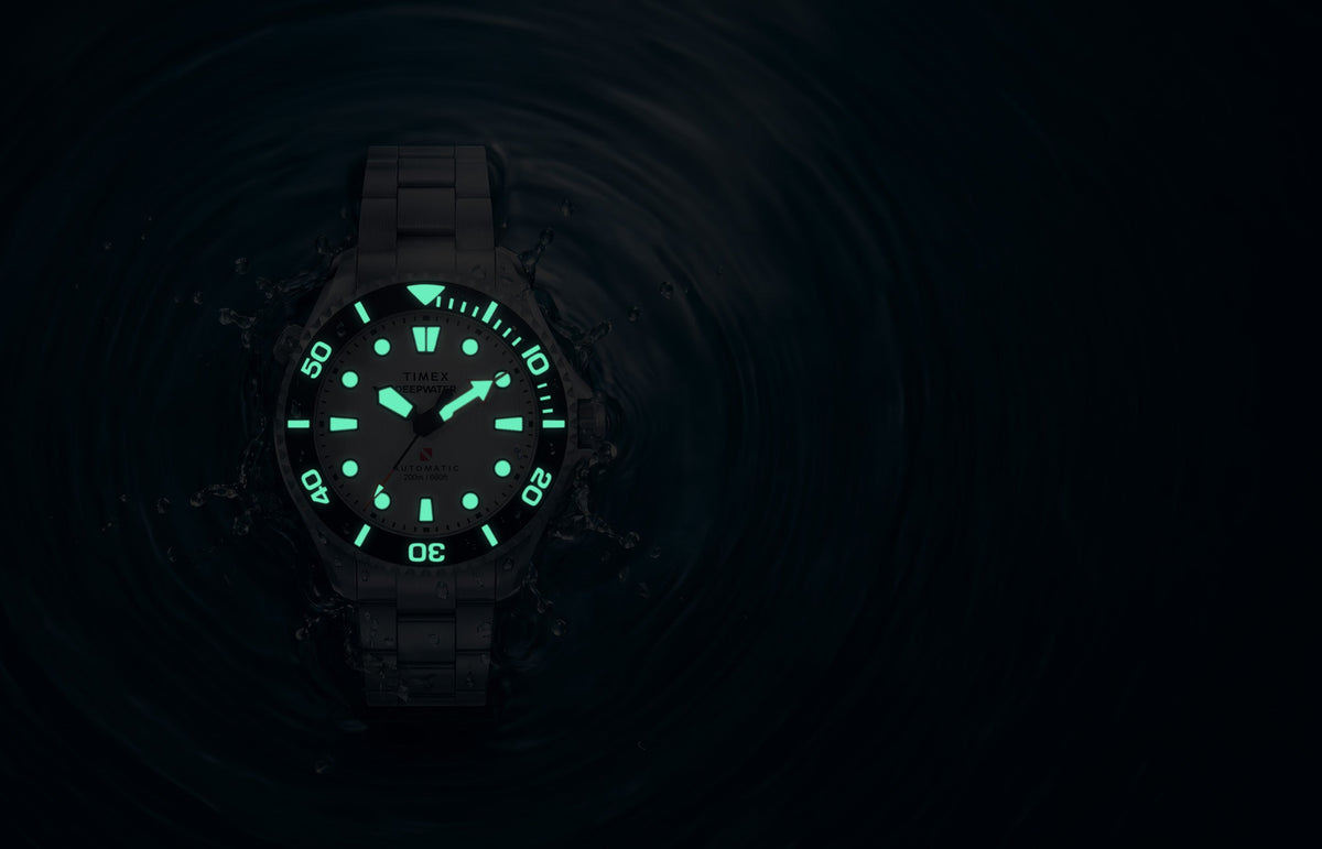 Deepwater Meridian 200 HEV Automatic surrounded by water in low light with illuminated dial and bezel markers.
