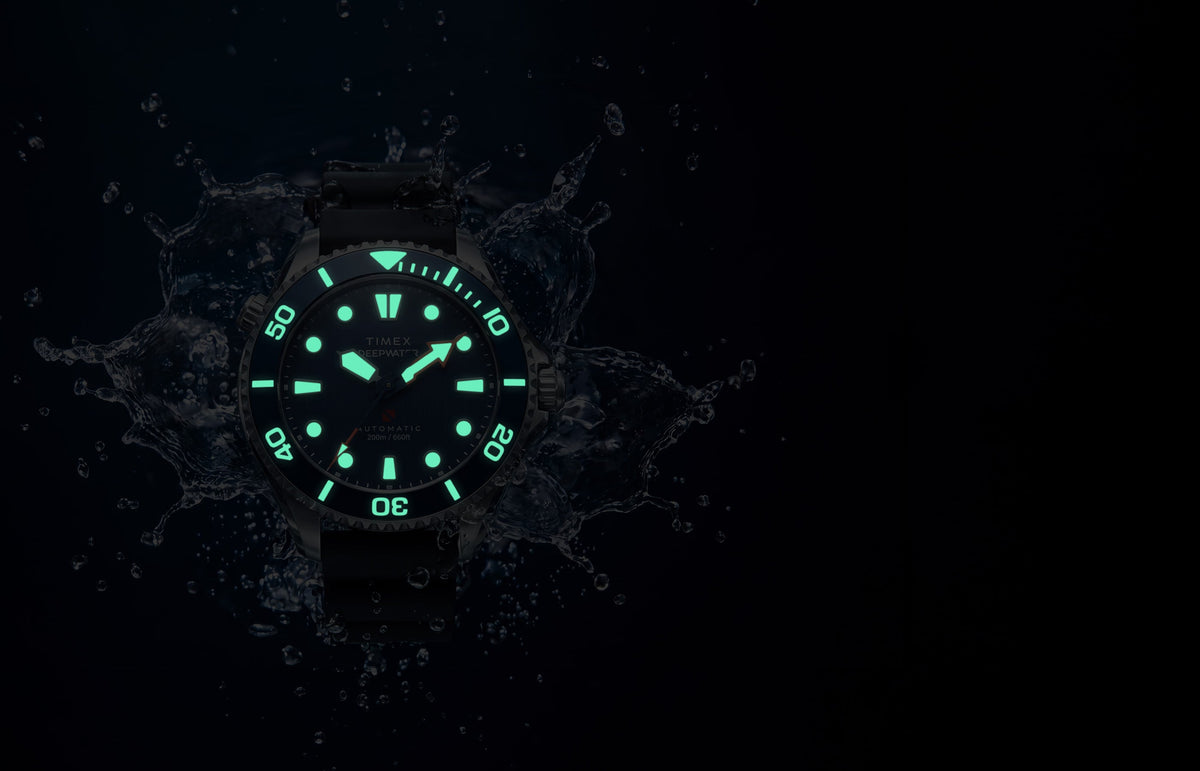 Deepwater Meridian 200 HEV Automatic surrounded by water in low light with glowing dial and bezel markers.