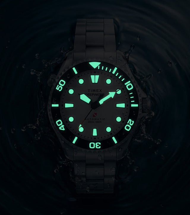 Deepwater Meridian 200 HEV Automatic surrounded by water in low light with illuminated dial and bezel markers.