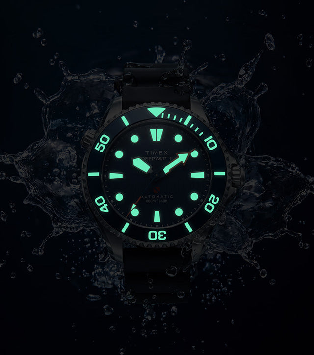 Deepwater Meridian 200 HEV Automatic surrounded by water in low light with glowing dial and bezel markers.