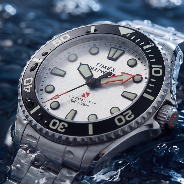 Close-up of the Deepwater Meridian 200 HEV Automatic’s silver-tone dial, luminous markers, red arrow hands, and black dive bezel.