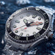 Close-up of the Deepwater Meridian 200 HEV Automatic’s silver-tone dial, luminous markers, red arrow hands, and black dive bezel.