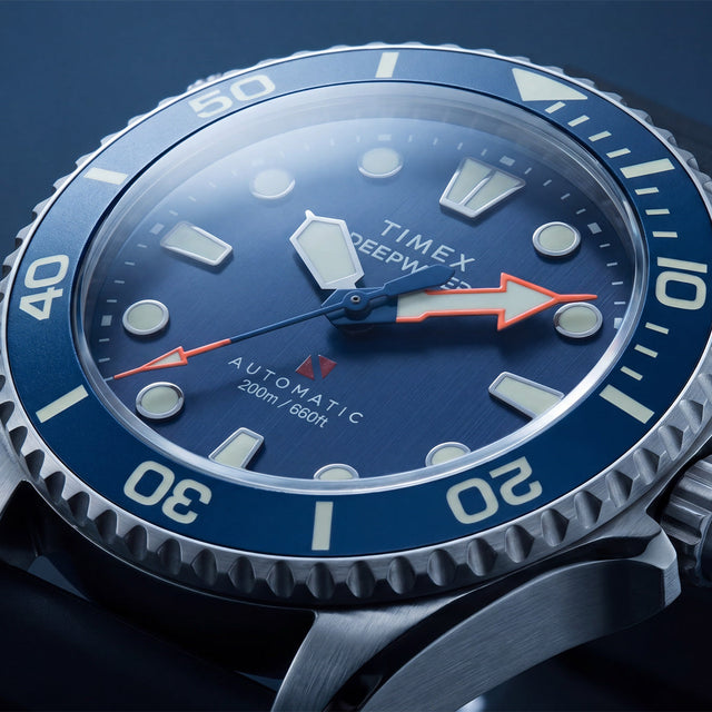 Close-up of the Deepwater Meridian 200 HEV Automatic’s blue dial, luminous markers, red arrow hands, and rotating bezel.