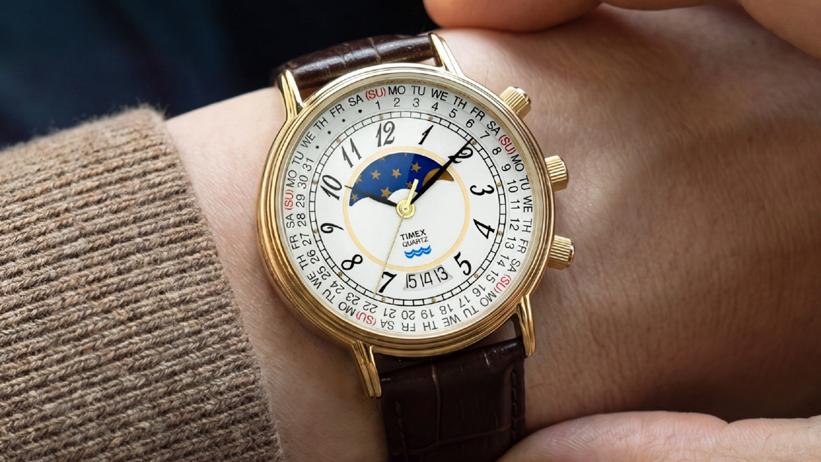 Timex 1990 Moon Phase and Calendar Dial Reissue worn on the wrist with its gold-tone case, white dial, and brown leather strap in view.