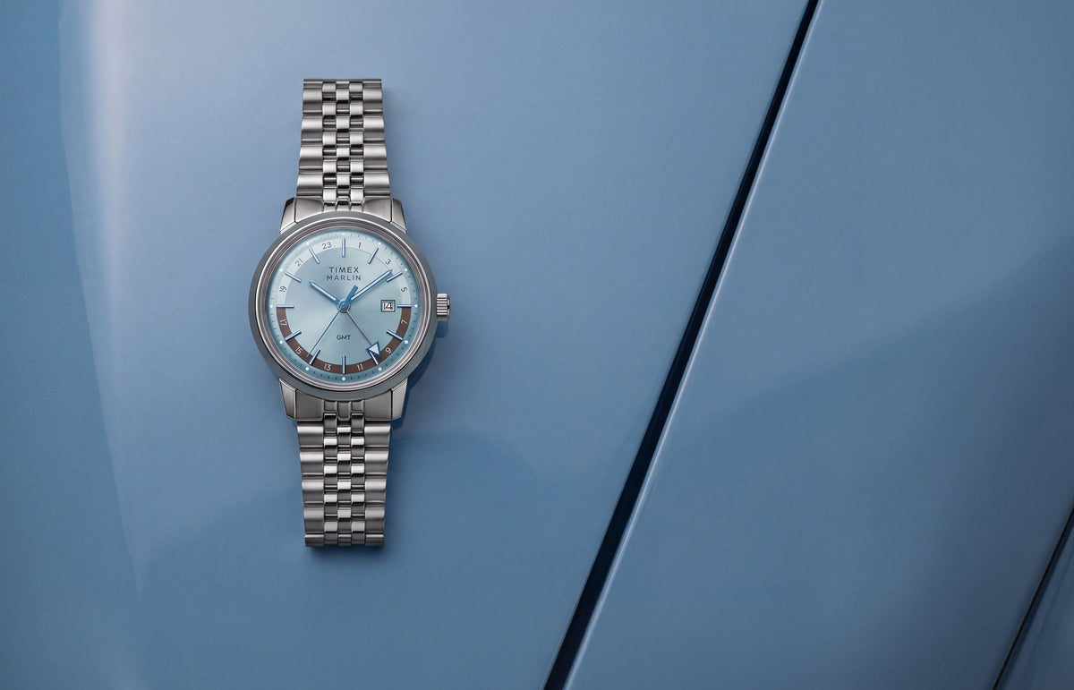 Marlin® Quartz GMT with an icy blue dial and stainless-steel bracelet displayed on a blue surface.