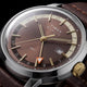 Detailed close-up of the Marlin® Quartz GMT brown dial, gold-tone markers, orange GMT hand, and date window.