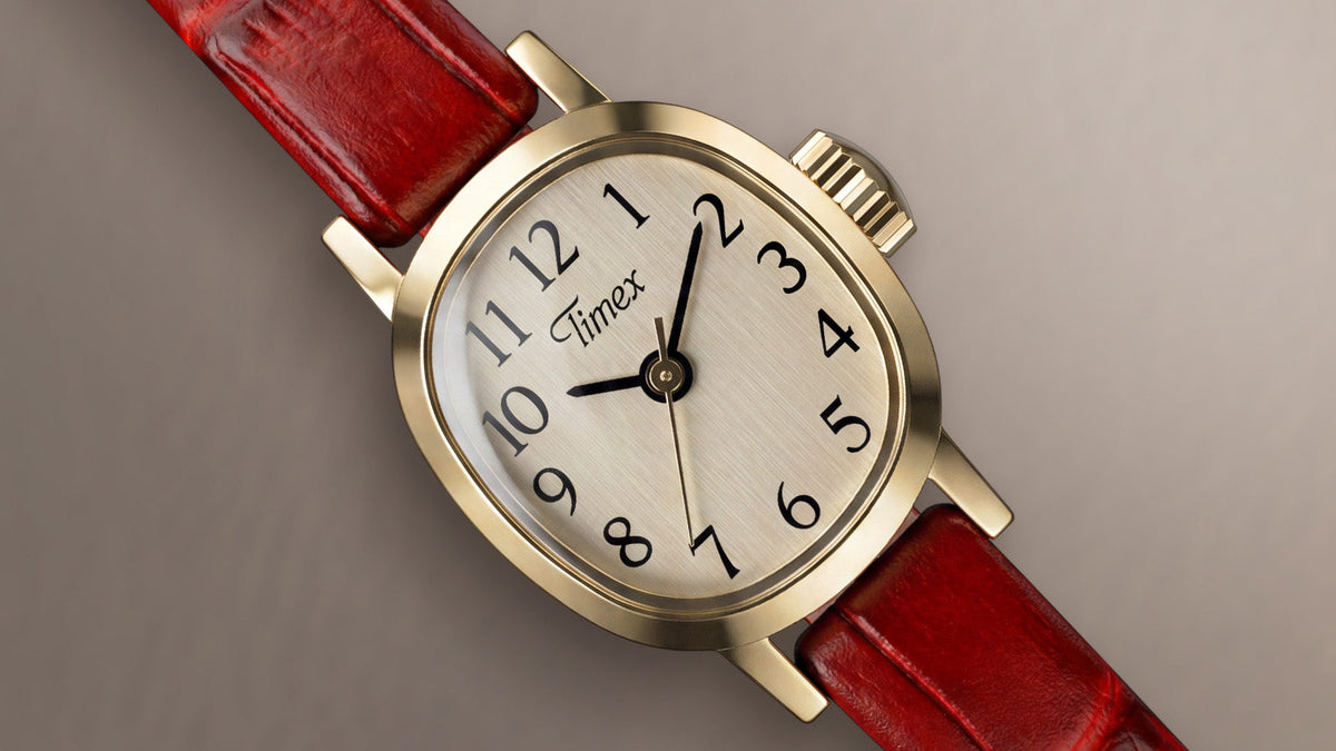 Close-up of the Cavatina® Mini featuring a gold-tone case, champagne dial, black Arabic numerals, and red leather strap.