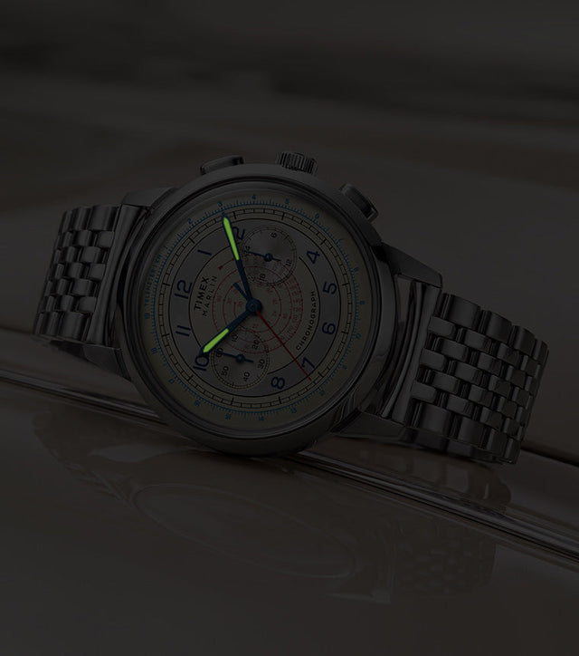 Marlin® Neo Classic Chronograph resting on a cream-colored car in low light with green luminous hands.
