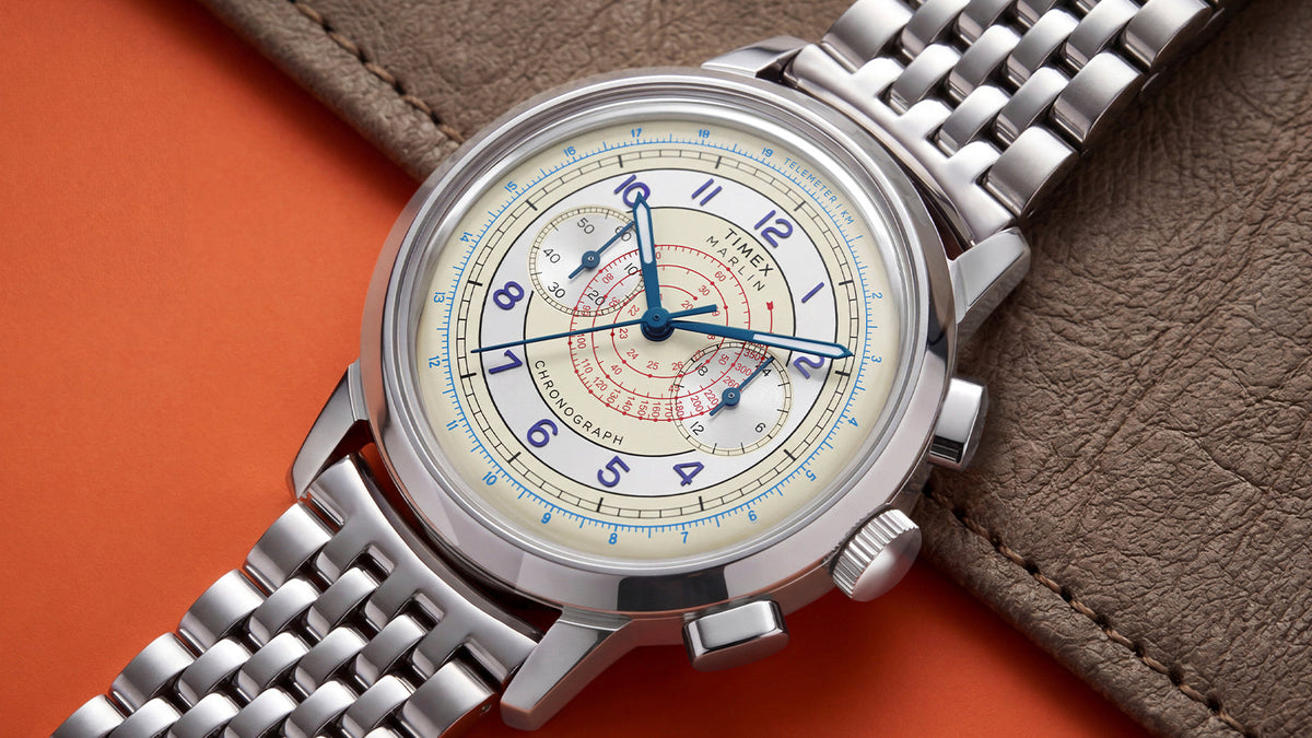 Marlin® Neo Classic Chronograph displayed on an orange surface beside textured gray leather.