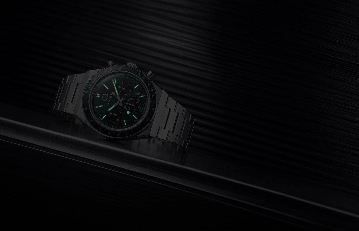 Q Timex Chronograph in low light, highlighting the glowing hands and hour markers.