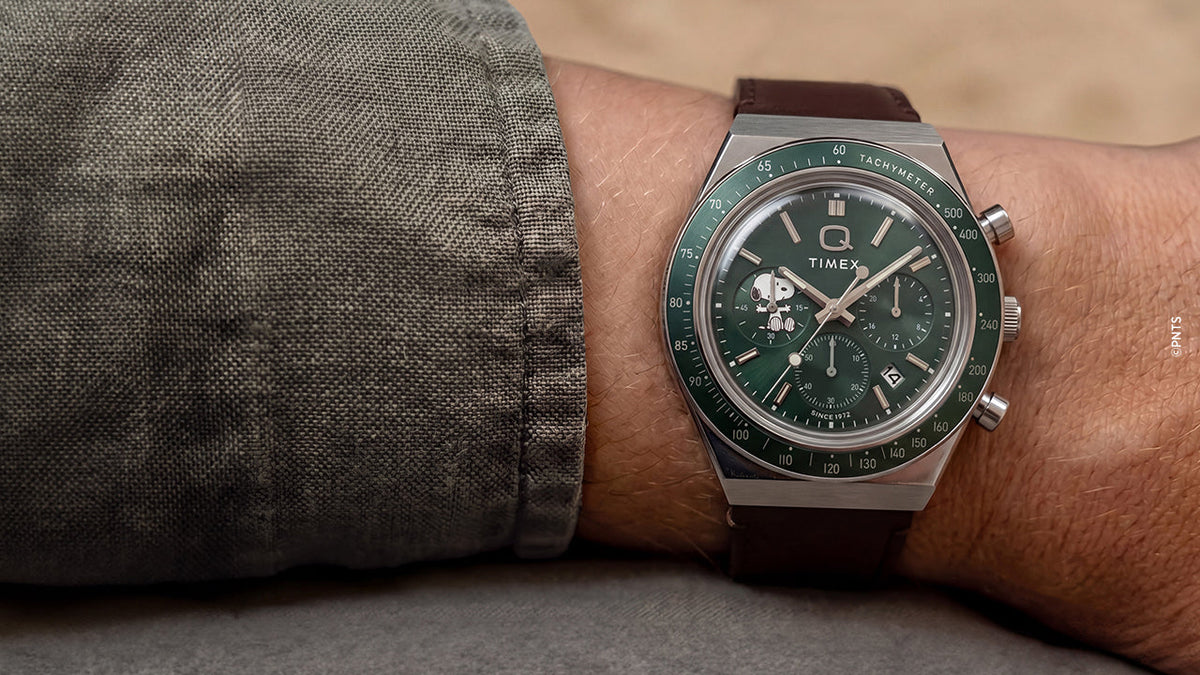 Peanuts® x Q Timex Chronograph with a green dial and brown leather strap worn on the wrist.