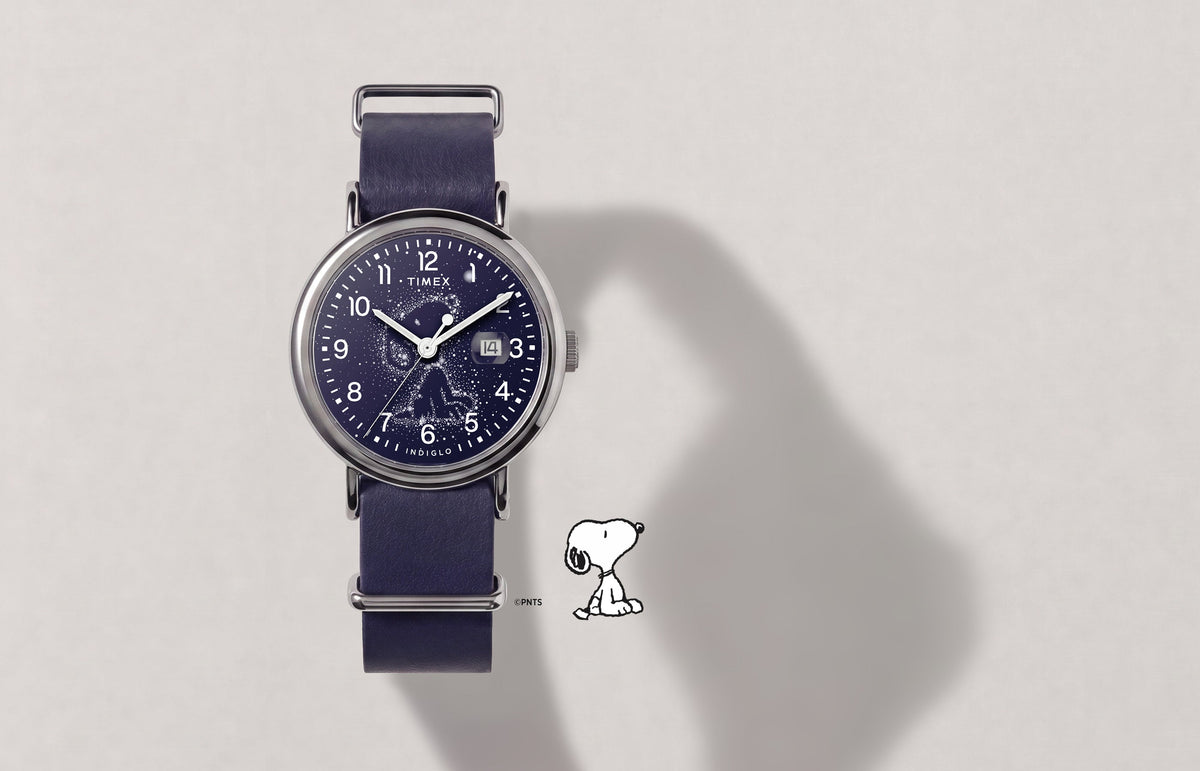 Peanuts® x Timex Weekender Astronomy watch with a navy strap, silver-tone case, Snoopy constellation dial, and date window.