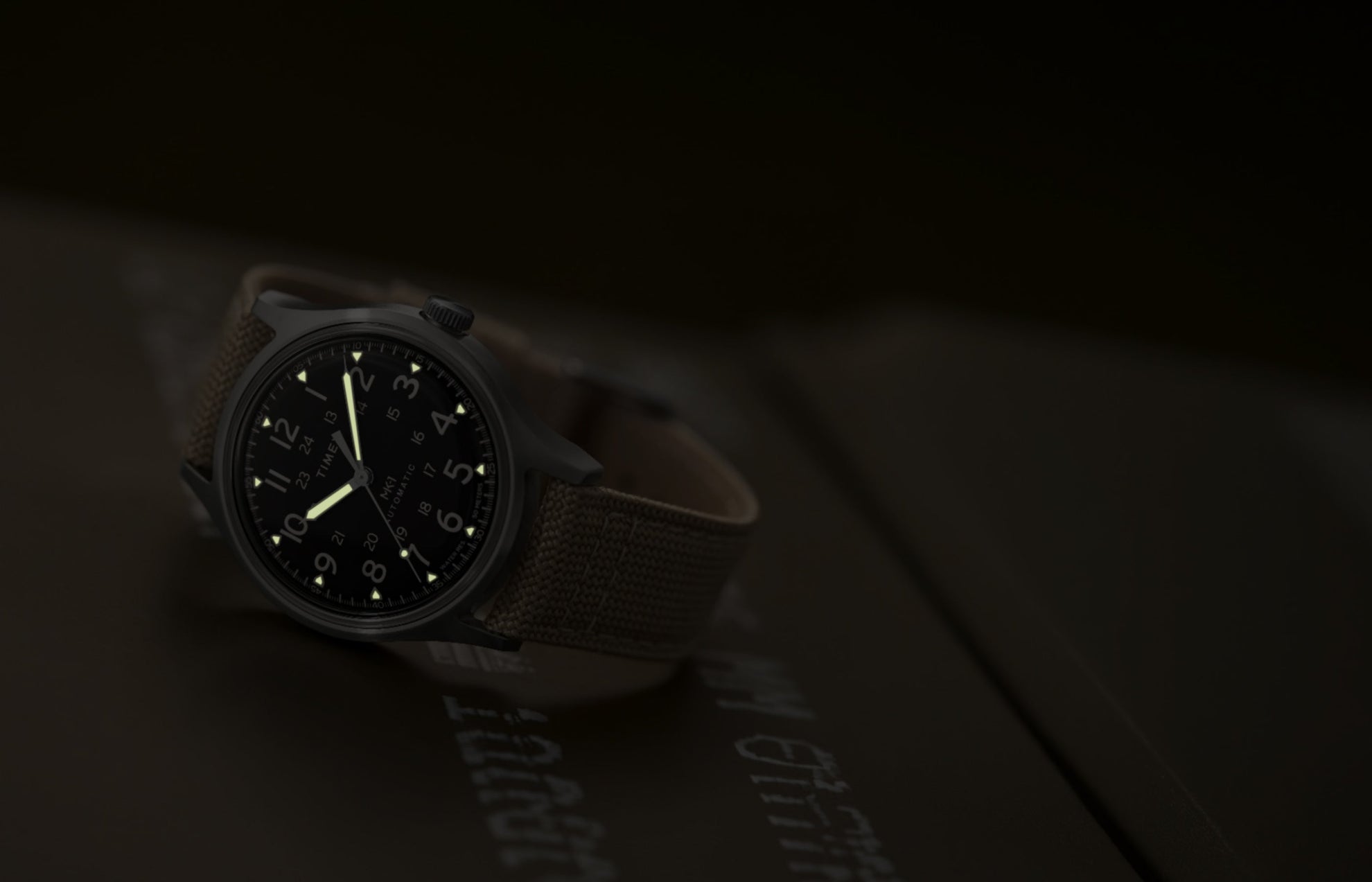 MK1® Automatic watch in low light, highlighting its glowing hands and hour markers.