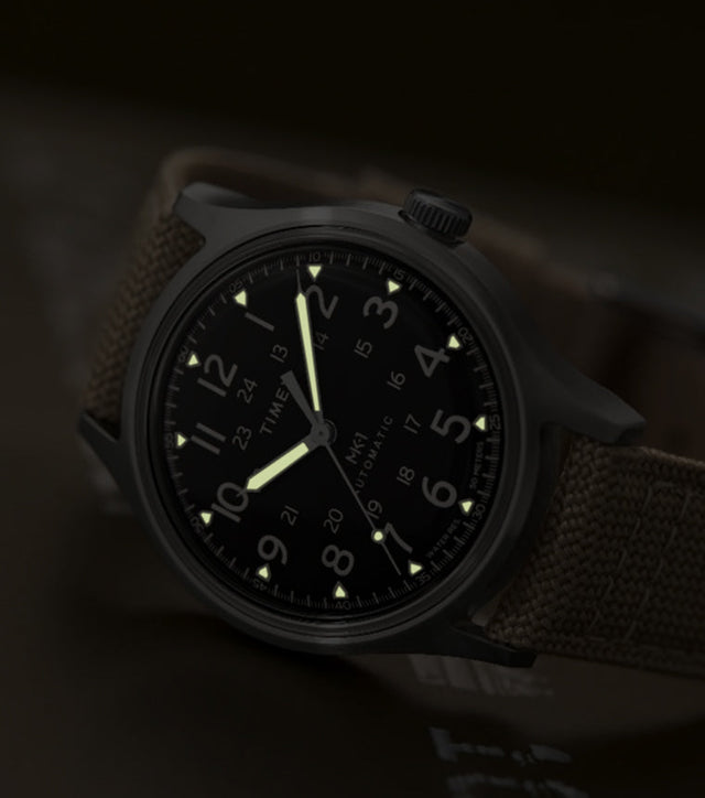 MK1® Automatic watch in low light, highlighting its glowing hands and hour markers.