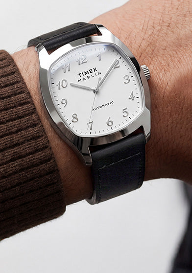 TW2Y84300 Marlin® Chatham Automatic watch worn with a brown knit sweater, featuring a white dial and black leather strap.