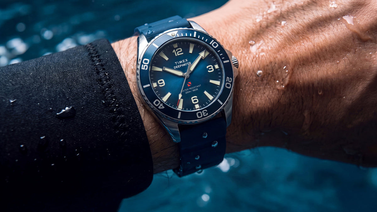 TW3A01900 Deepwater Arctic 200 watch with a blue dial and strap worn on a wet wrist near the water.