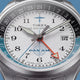 TW2Y94600 Macro view of the textured white dial with black numerals, Pan Am logo, orange GMT hand, and date window.