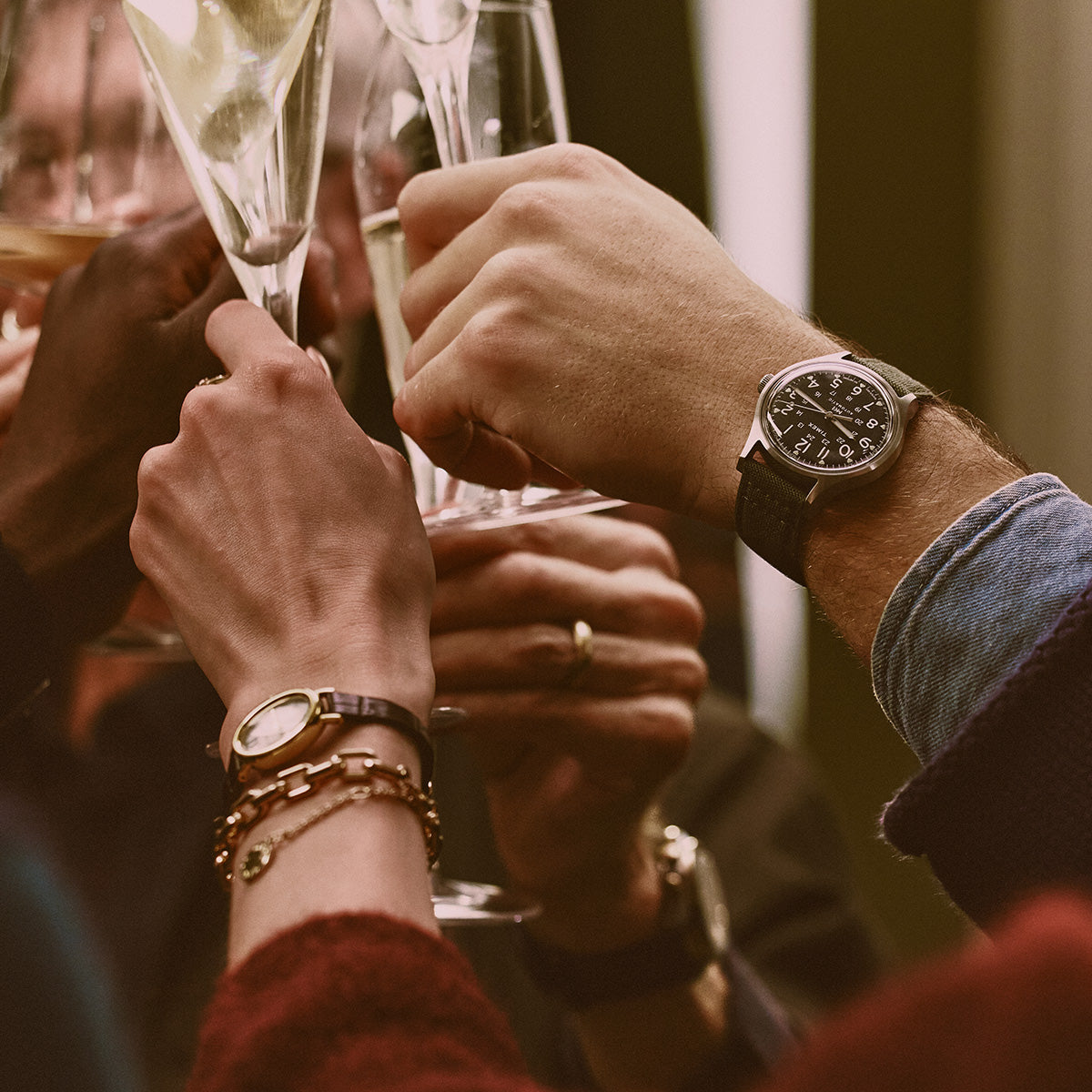 Friends raising champagne glasses, with Timex watches visible on two wrists.