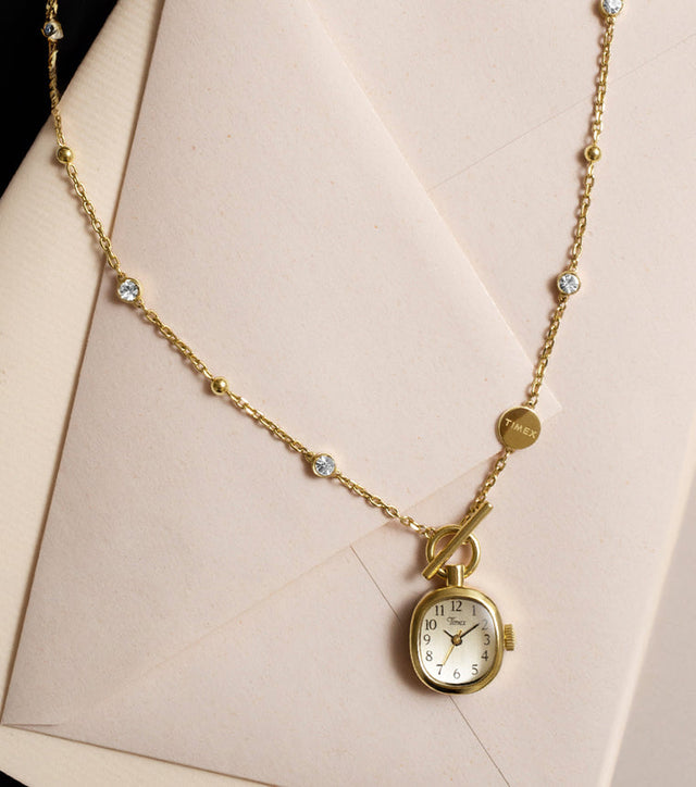TW6A17700 Gold-tone Cavatina® Mini watch necklace with clear stones and a toggle clasp, displayed on cream stationery.