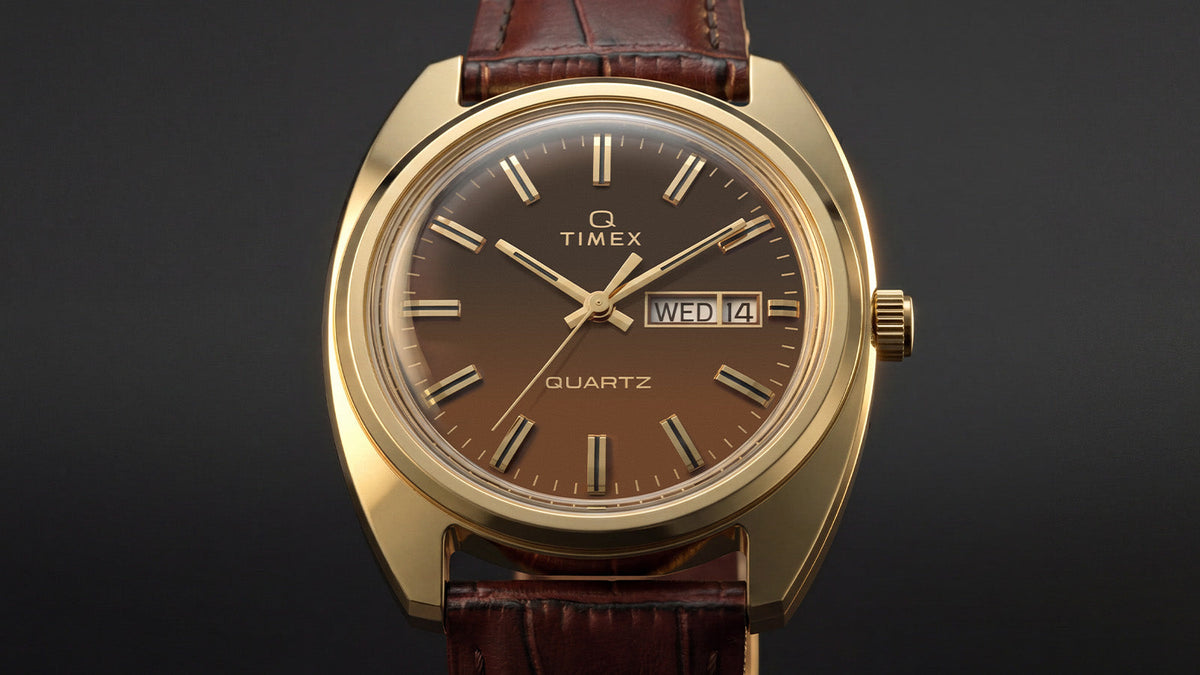 TW2Y87200 Front view of the Timex 1978 Day Date Fumé Reissue with a gold-tone case, brown gradient dial, and textured brown leather strap against a dark background.