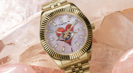 Jacquie Aiche heart dial watch with a rose quartz background behind. 