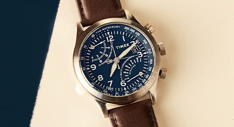 Brown leather strap watch with a dark blue dial and intericate detailed face with white markings. 