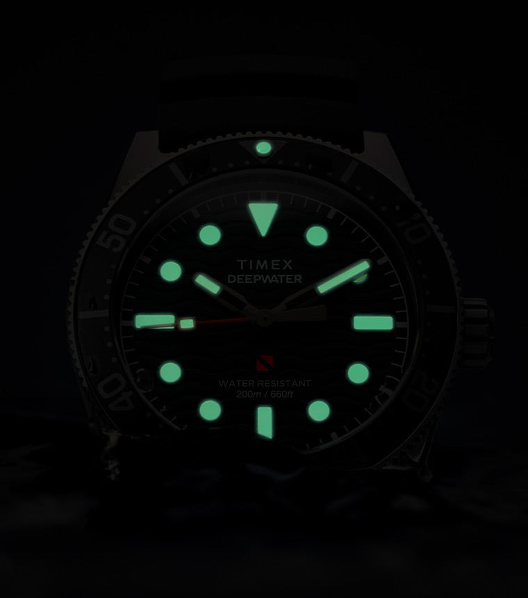 Glow-in-the-dark view of the Timex Deepwater Reef 200. The hour markers, hands, and bezel pip shine bright green, offering high visibility in low-light or underwater conditions, while the dial remains subtly visible.