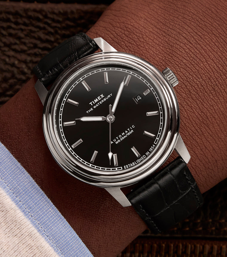 Timex watch with black face and leather strap on a wrist