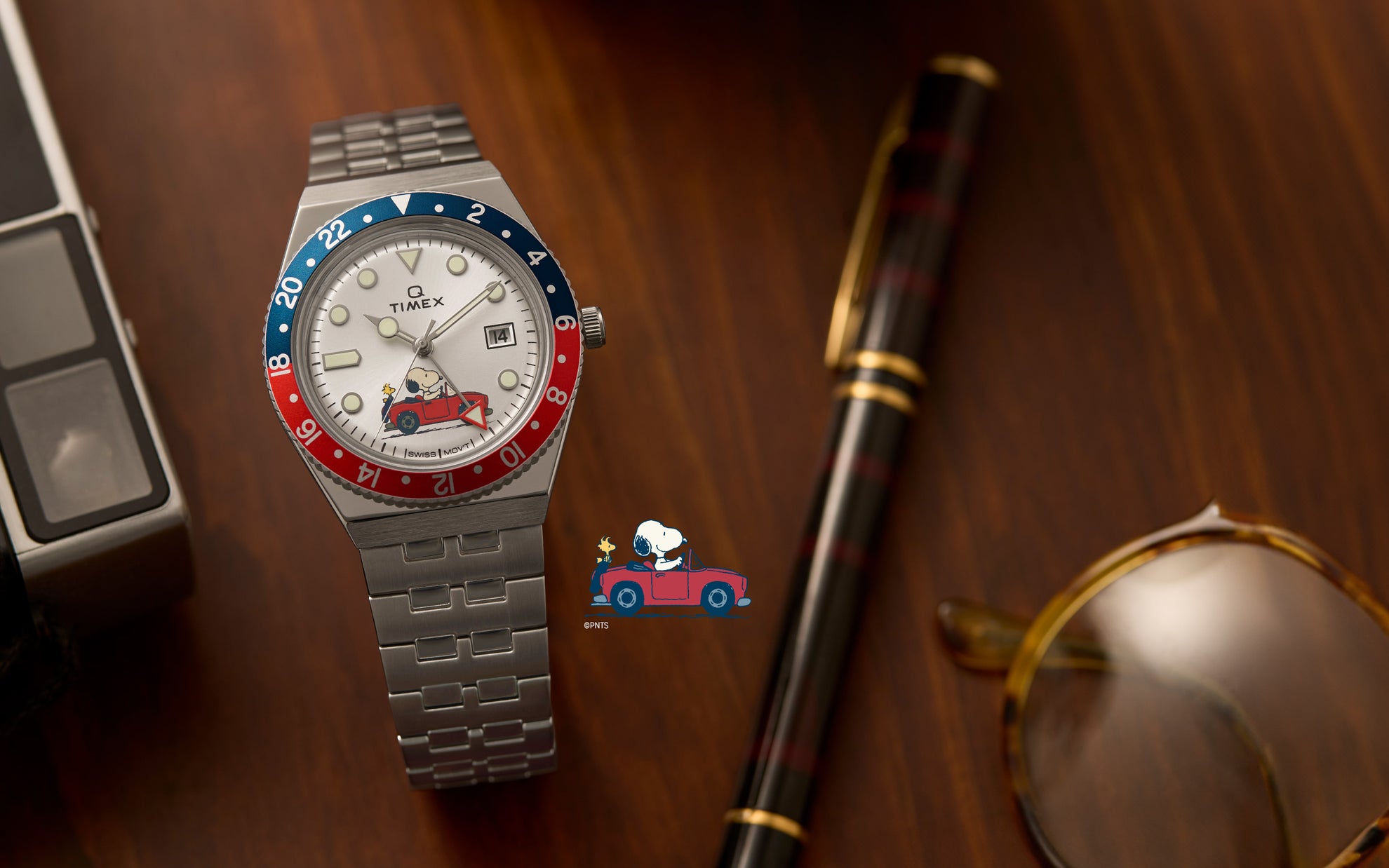 Peanuts	Q GMT Peanuts Red Car White Dial Silver-tone Bracelet with Snoopy riding in a car and woody at the back.