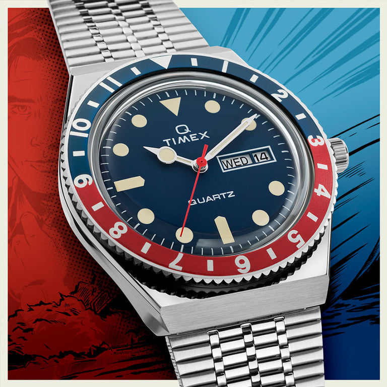 A Timex Q Reissue watch with a Pepsi bezel (red and blue), navy blue dial, and cream-colored luminescent hour markers. The stainless steel case and woven bracelet are styled over a pop-art comic backdrop in red and blue.