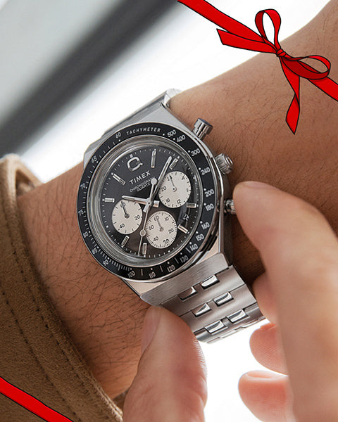 Close up image of a persons wrist with a stainless steel and black chronograph watch.