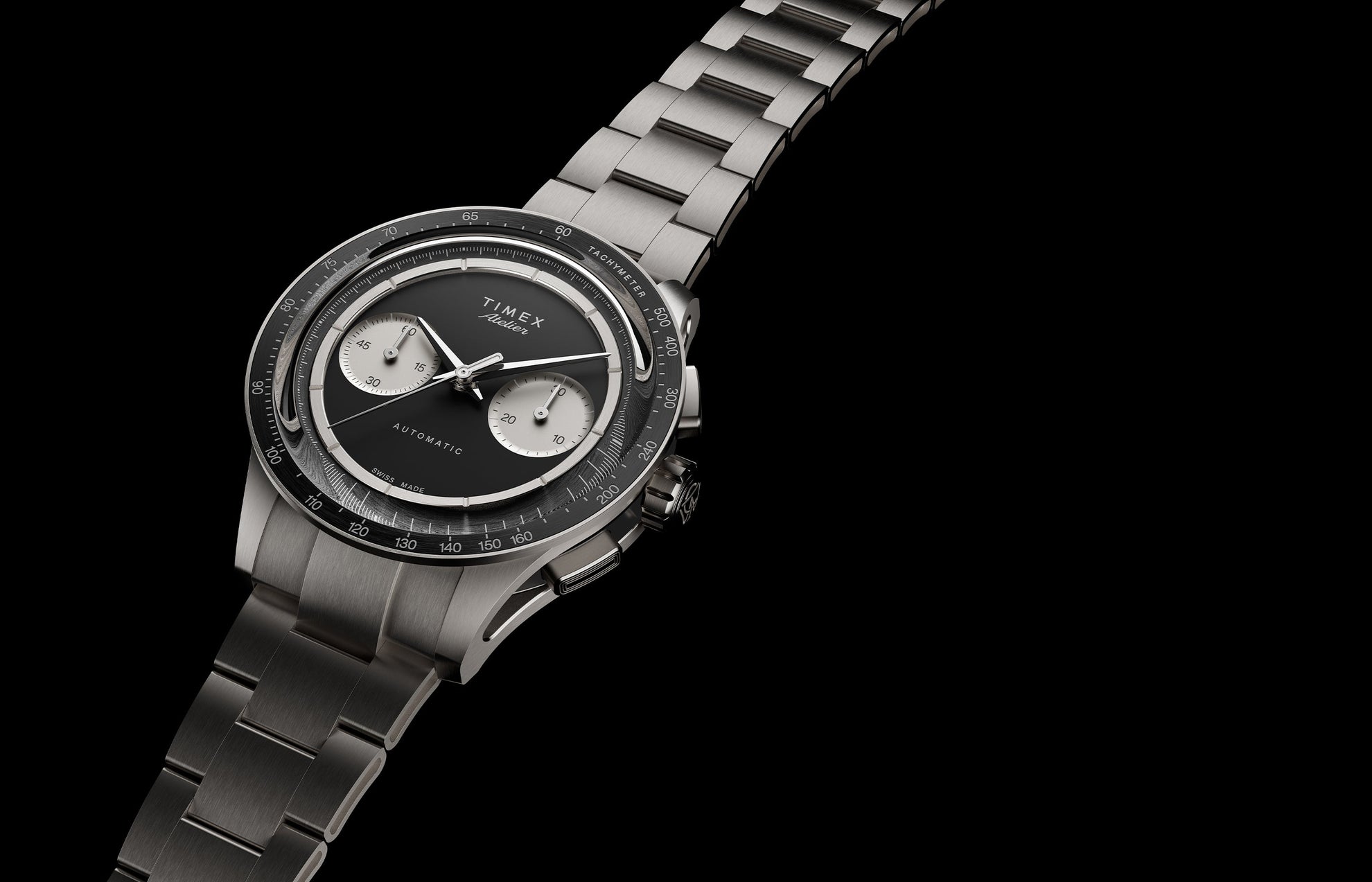 Timex Atelier Chronograph Automatic M1a Ti titanium watch with black dial, twin silver sub-dials, tachymeter bezel, and integrated titanium bracelet shown at an angled perspective.
