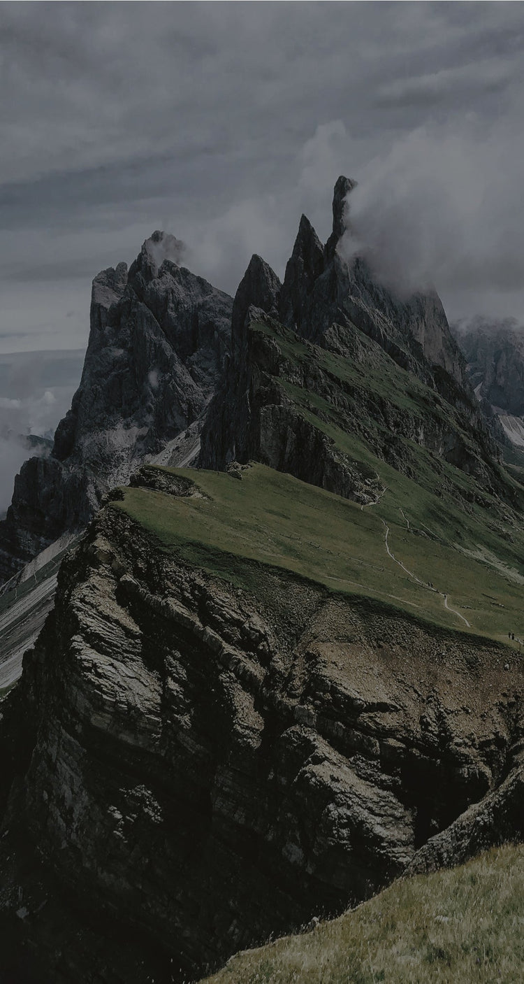 A photo of rocky mountain with clouds above the top of it