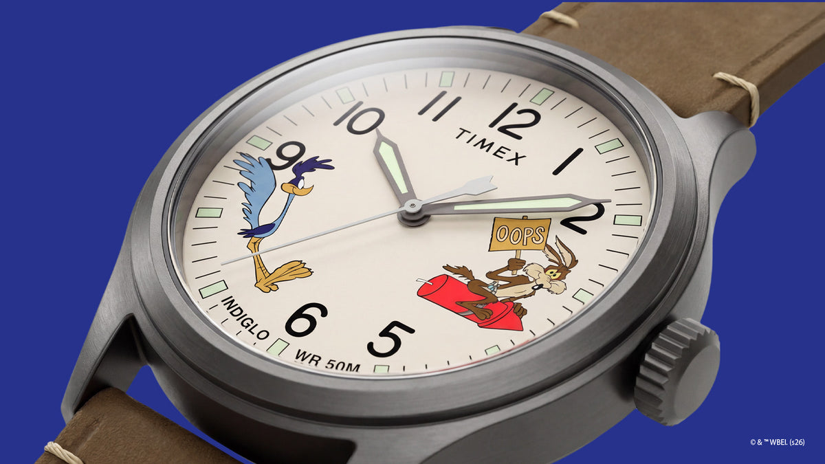 TW2Y99400 Angled view of the Road Runner & Wile E. Coyote watch showing its cream character dial, black numerals, gray case, and brown leather strap.