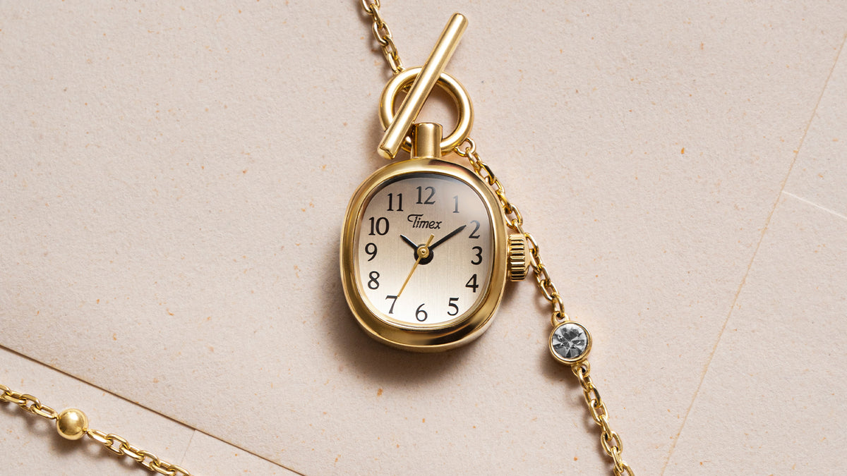 TW6A17700 Close-up of the Cavatina® Mini watch pendant, showing its gold-tone case, light dial, black numerals, and toggle clasp.